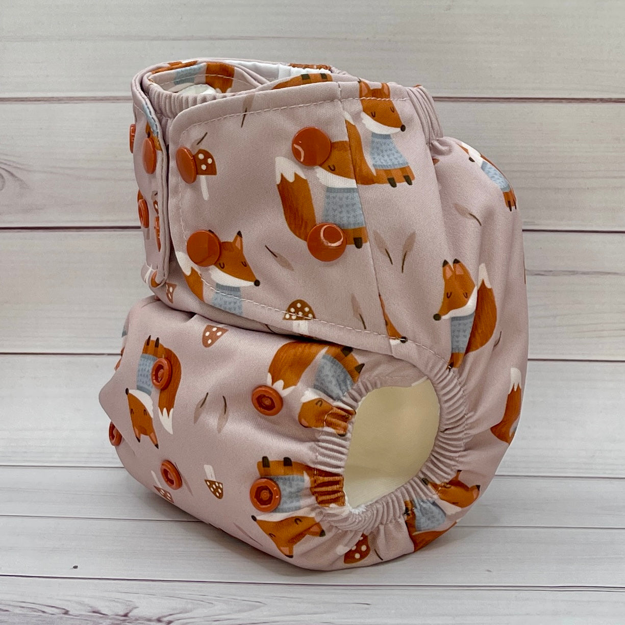 Two baby diapers with fox pattern on a wooden surface