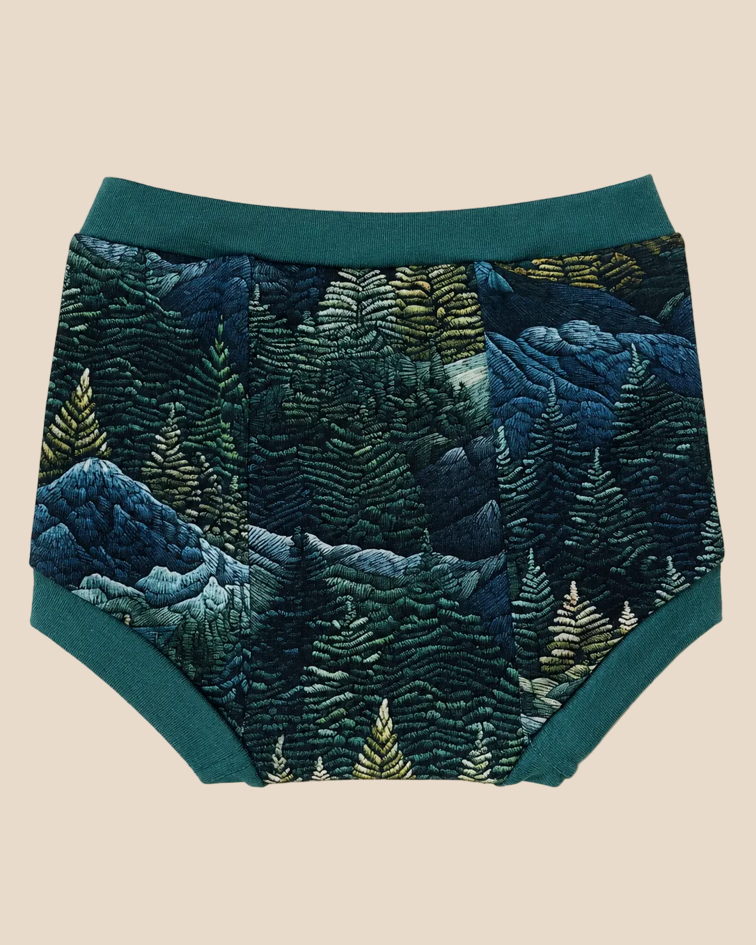 A pair of baby boy shorts featuring a detailed embroidered forest pattern in shades of blue, green, and beige, with solid teal green trim.