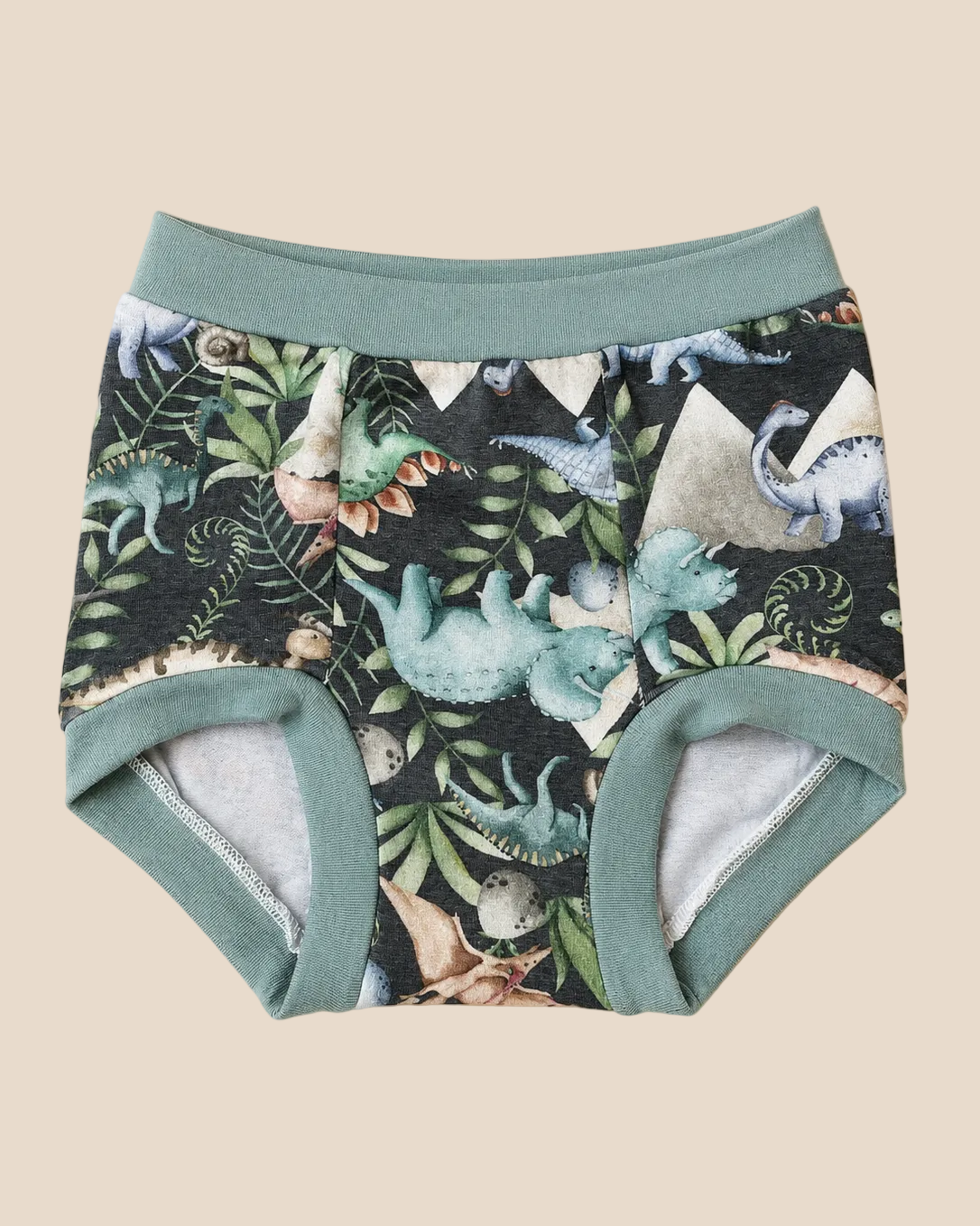 A pair of toddler boy's underwear with a dark green and black dinosaur print, featuring sage green trim and lining, laid flat on a light beige background.