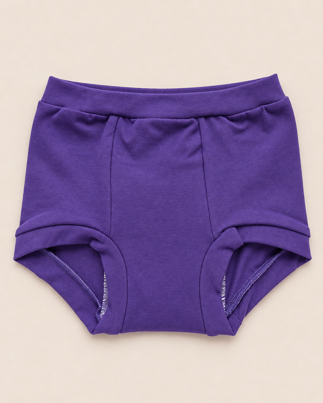 A pair of solid purple baby briefs laid flat on a light beige background.