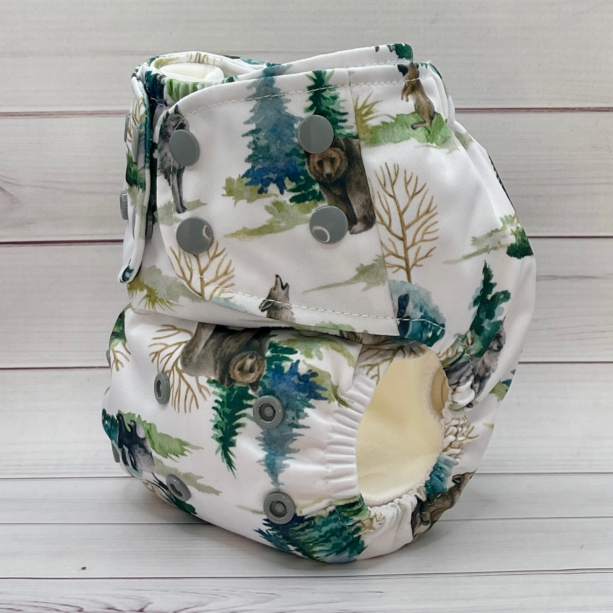 Reusable diaper with bear and forest pattern on a wooden surface