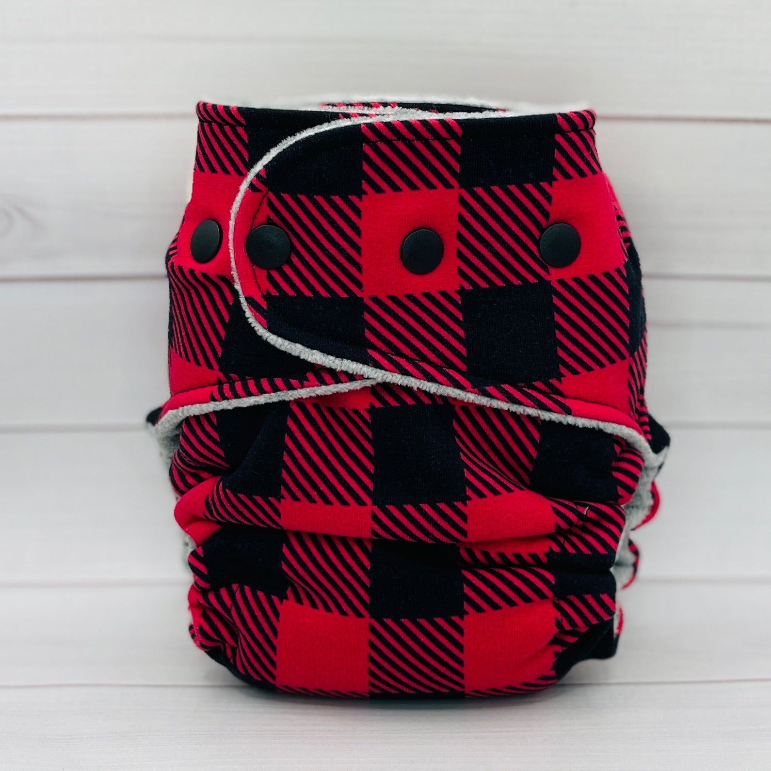 Red and black plaid diaper with buttons on a white background