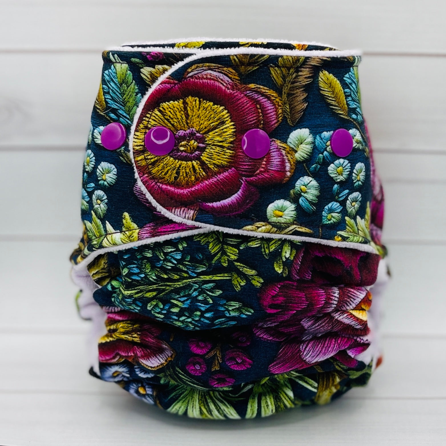 Floral patterned diaper with colorful buttons on a white background