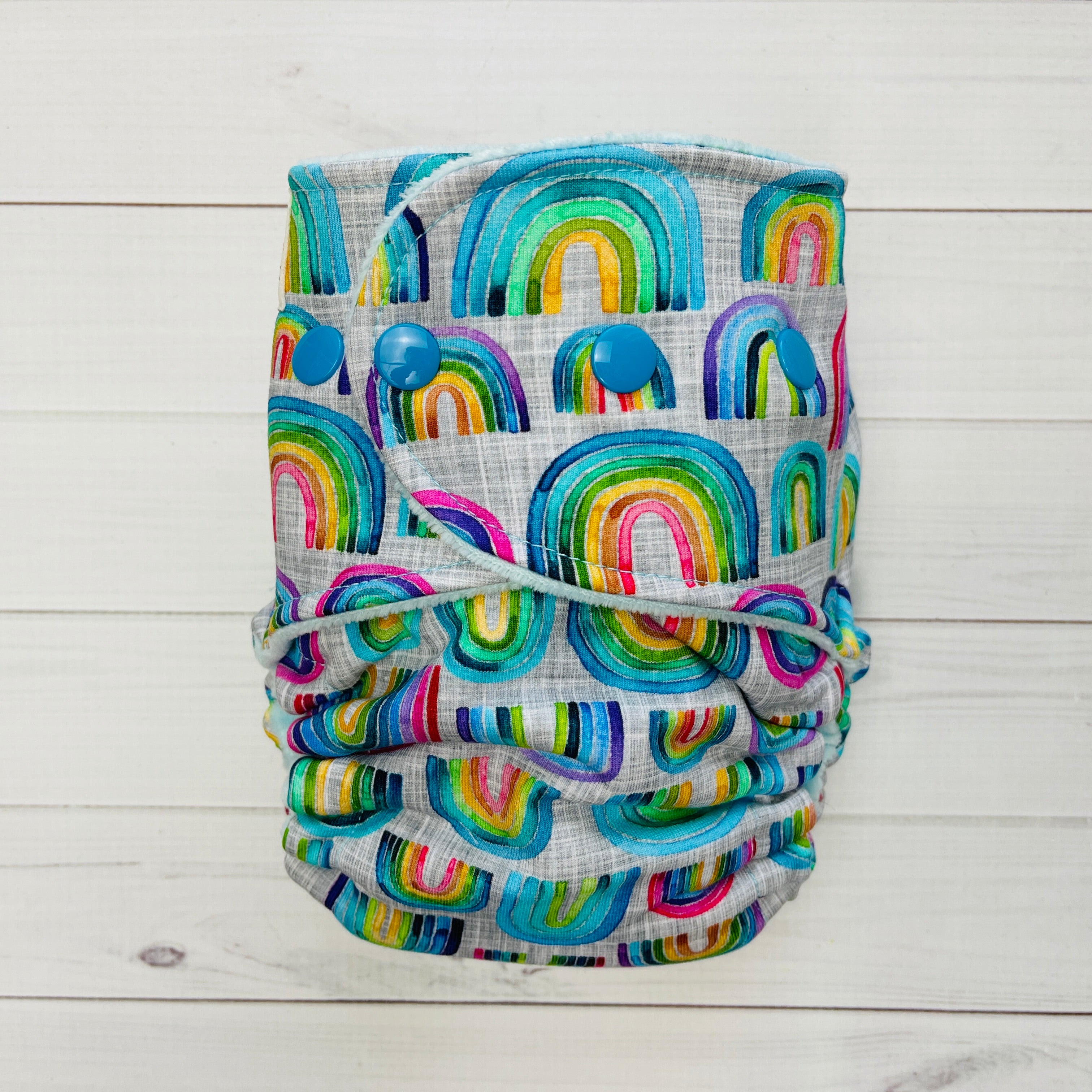 Fabric with colorful rainbow pattern on a white wooden background