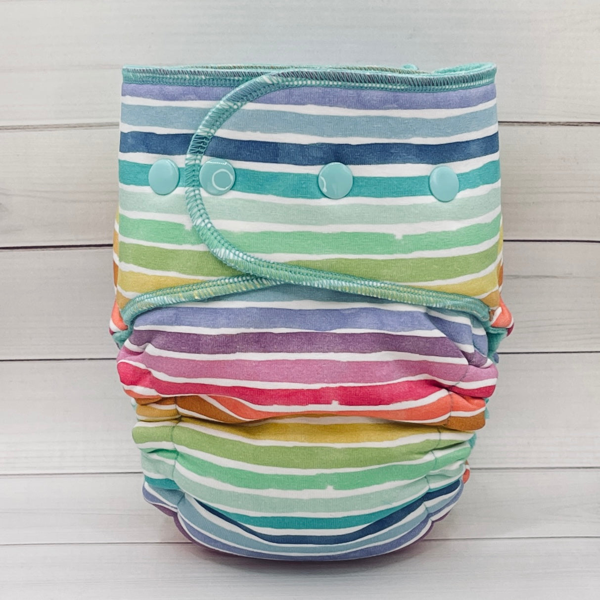Colorful striped cloth diaper on a light wooden background