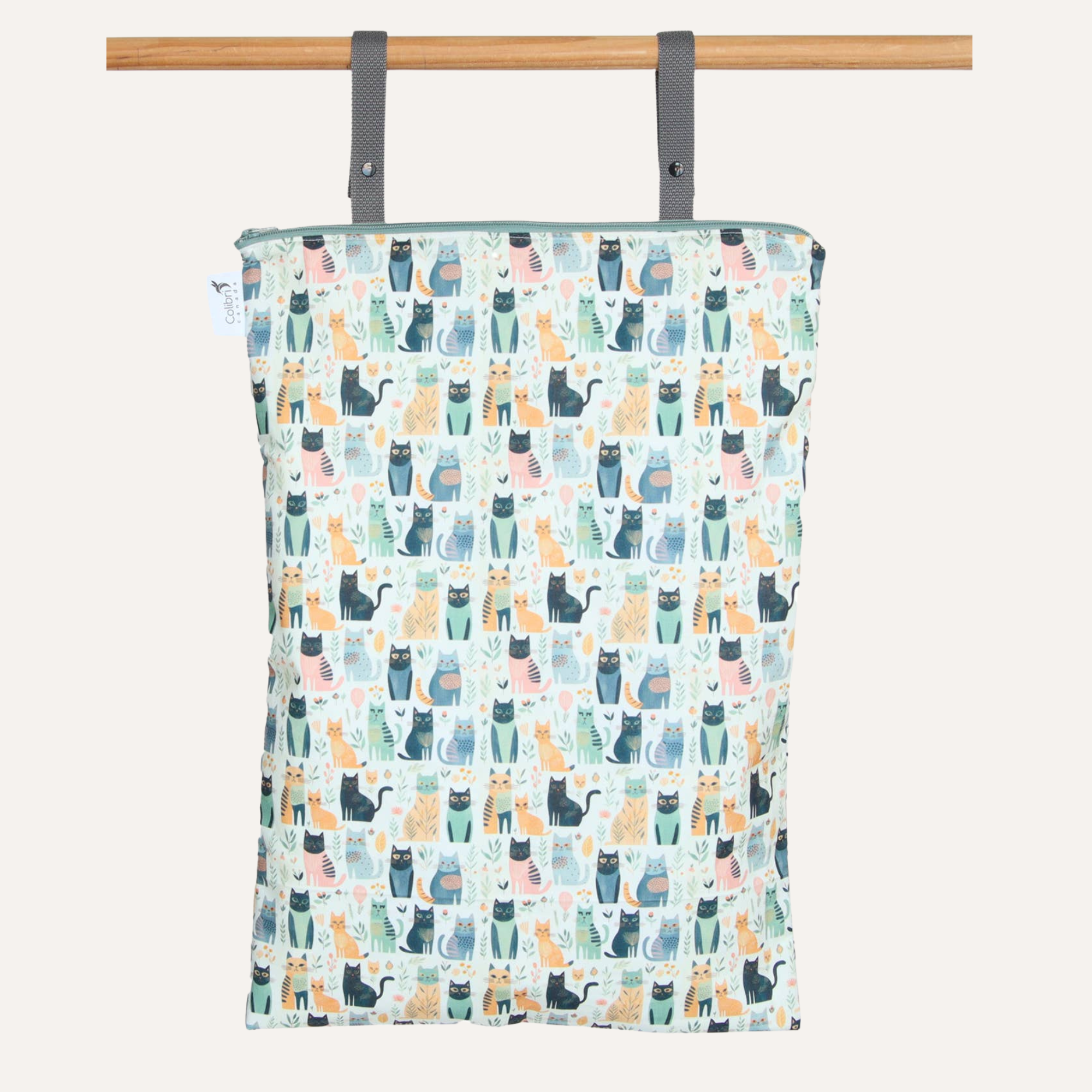 Patterned bag with cat design hanging on a wooden rod against a white background