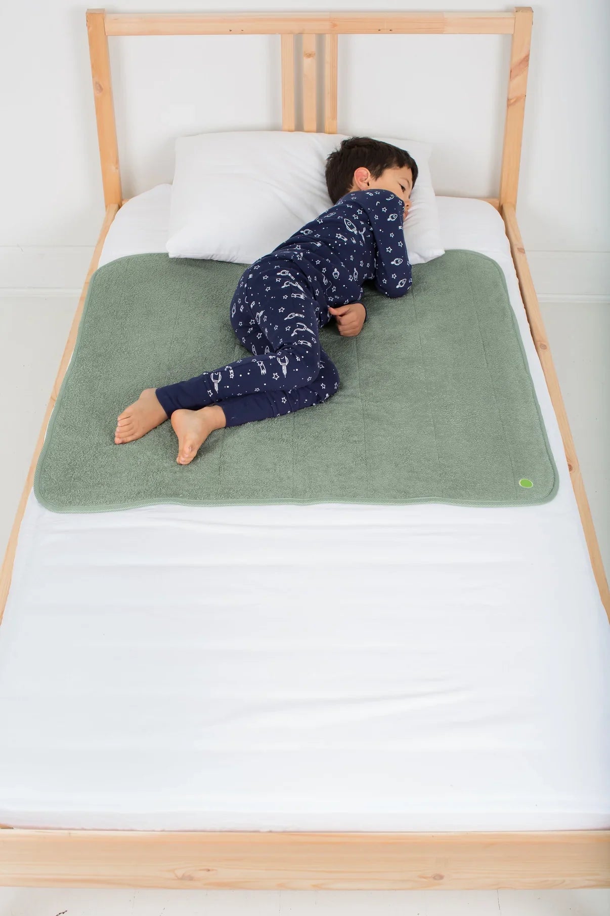 child sleeping on waterproof bed cover in sage green