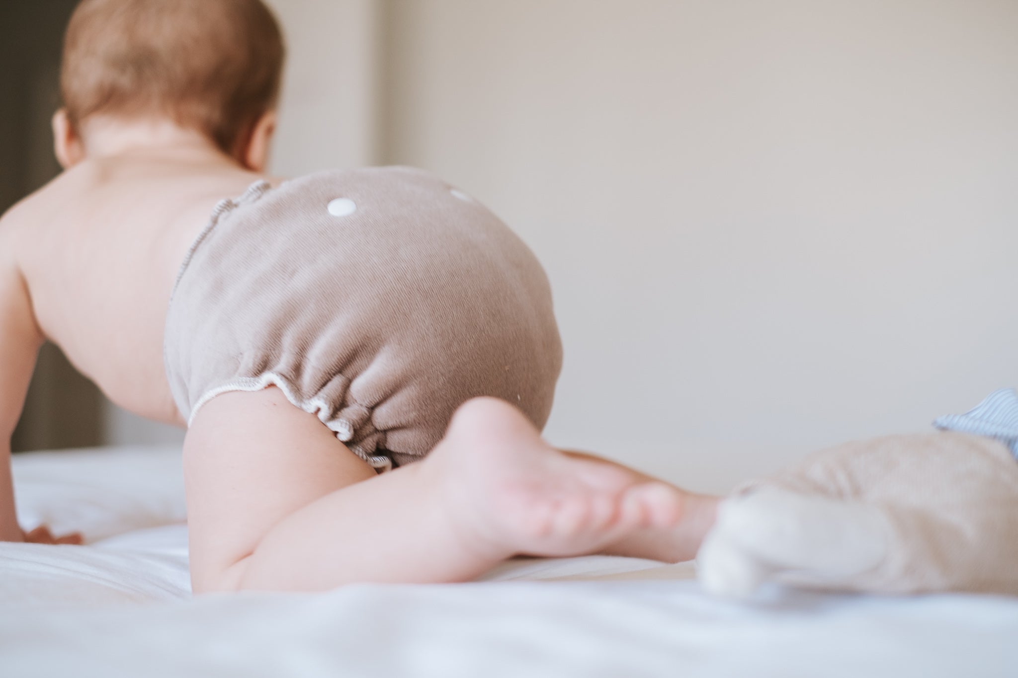 baby wearing a night time cloth daper on a bed