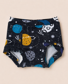 A pair of baby trainers with a dark navy blue space-themed print featuring colorful planets, stars, and comets, laid flat on a light beige background.