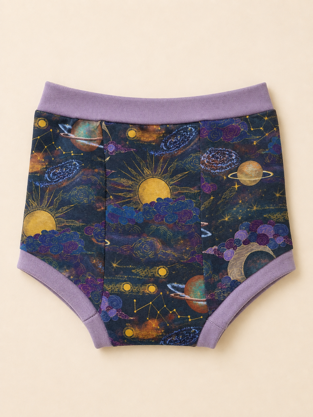 A pair of children's high-waisted briefs with a colorful outer space print featuring planets, stars, and suns on a dark navy background, finished with a solid lavender-purple waistband and leg cuffs, shown flat on a light beige background.