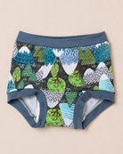 A pair of toddler boy's briefs featuring a colorful forest and mountain pattern with blue, green, and white motifs on a dark background, with solid blue ribbed waistband and leg cuffs, laid flat on a light beige background.
