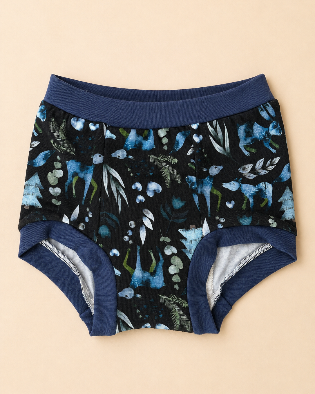A pair of toddler boy's briefs featuring a dark navy blue and black watercolor-style print of blue birds and green foliage, with solid navy blue elastic waistband and leg cuffs, laid flat on a light beige background.