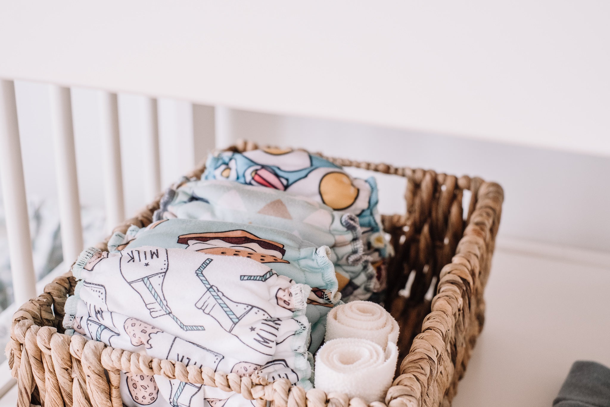 Wicker basket with folded cloth diapers on a white surface