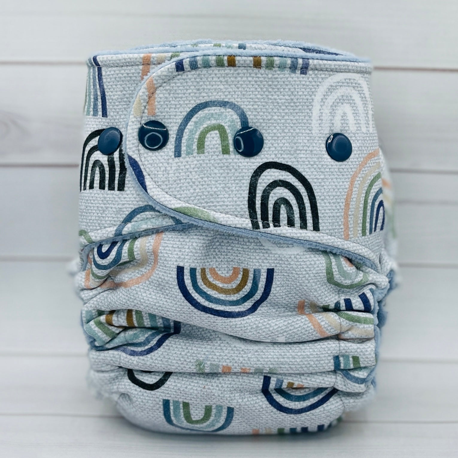 Rainbow patterned cloth diaper on a light wooden background