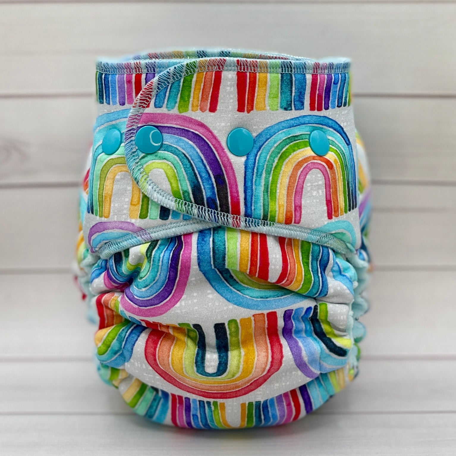 Colorful rainbow-patterned cloth diaper on a light wooden background