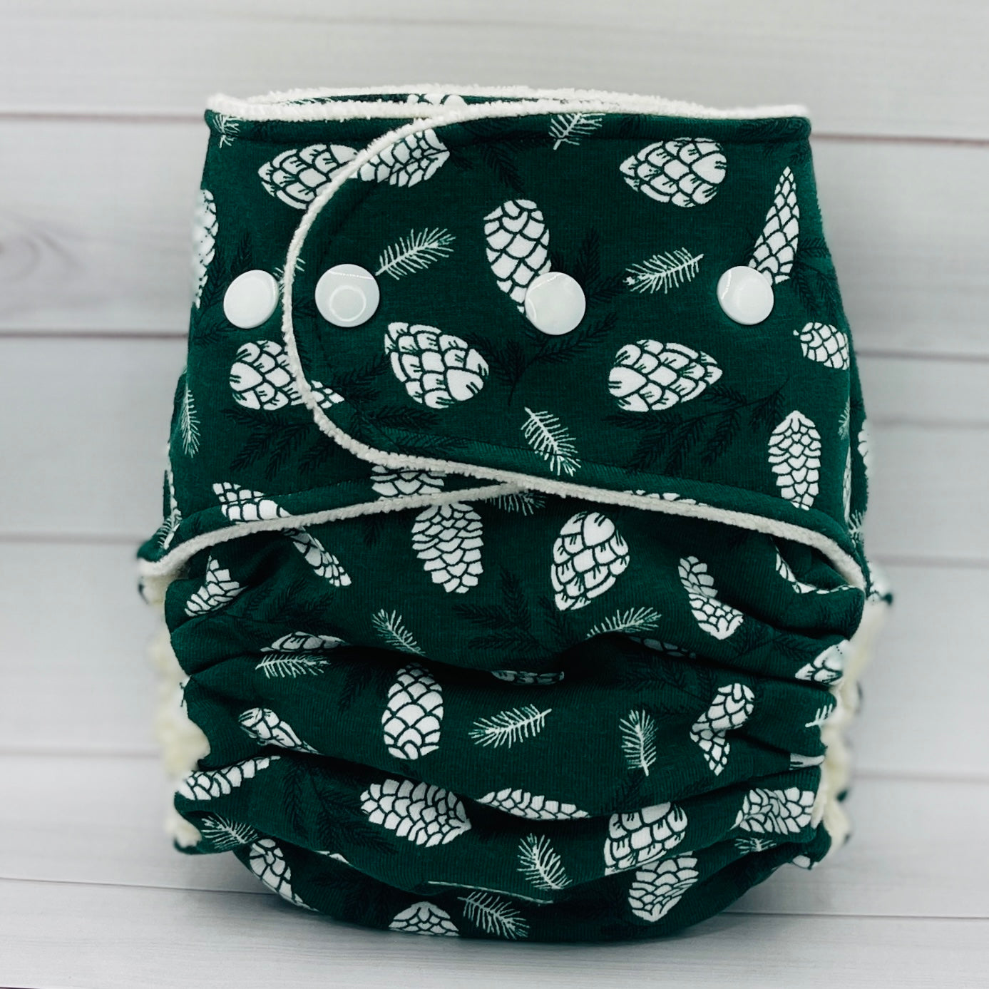 one size fitted diaper with dark green print and white pinecones
