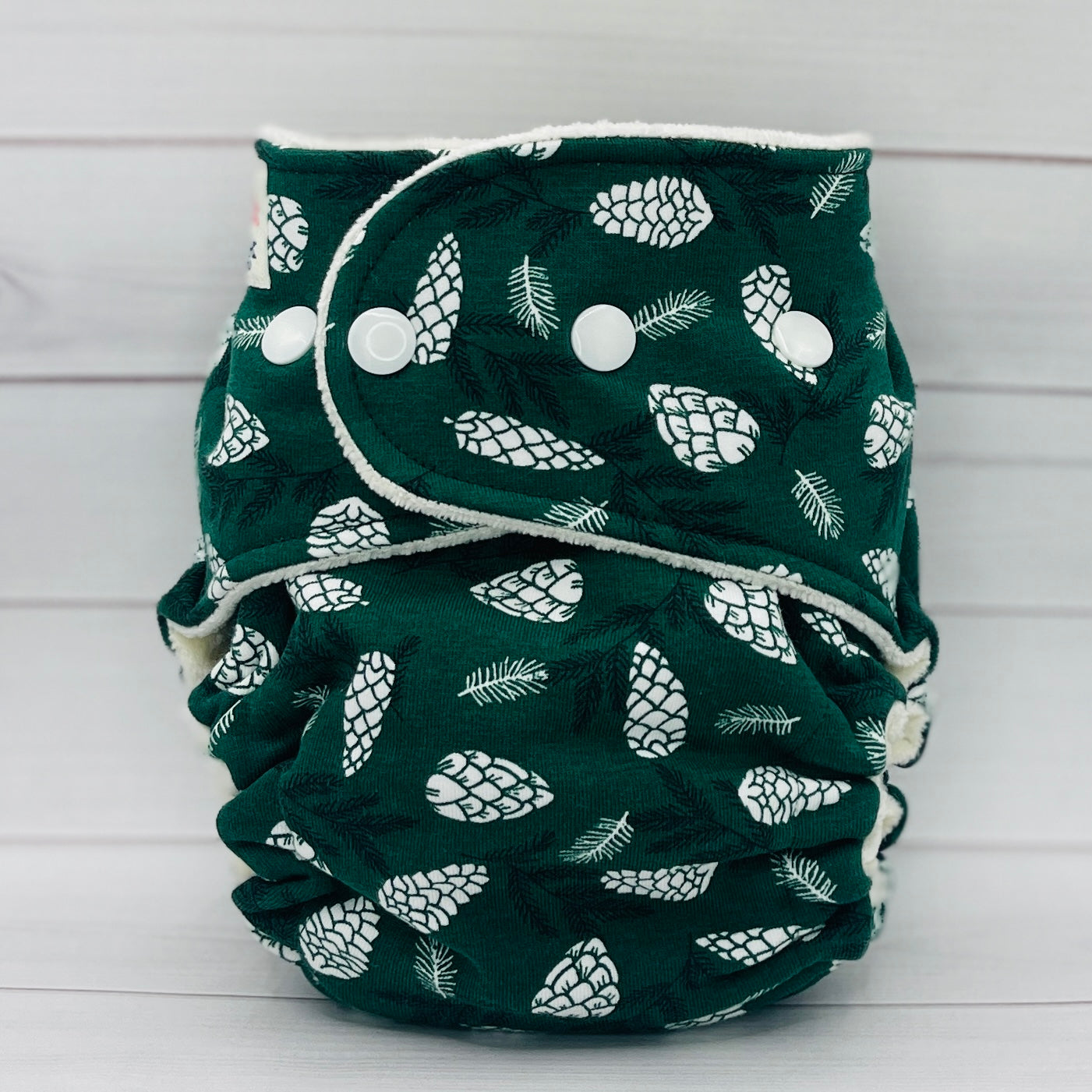 petite fitted diaper with dark green print and white pinecones