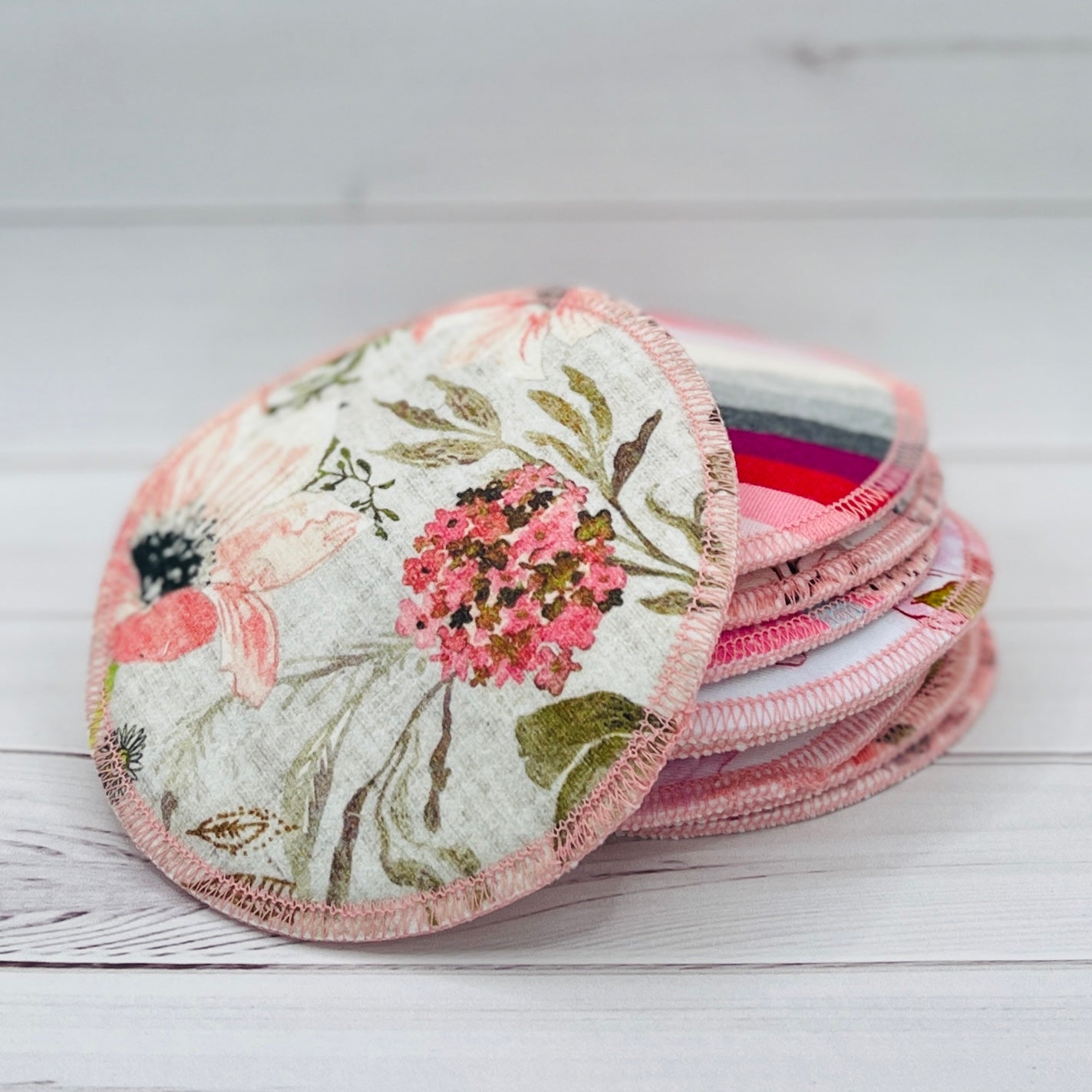 Set of floral-patterned reusable nursing pads on a wooden surface