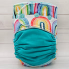 Turquoise cloth diaper with colorful rainbow pattern on a light wooden background