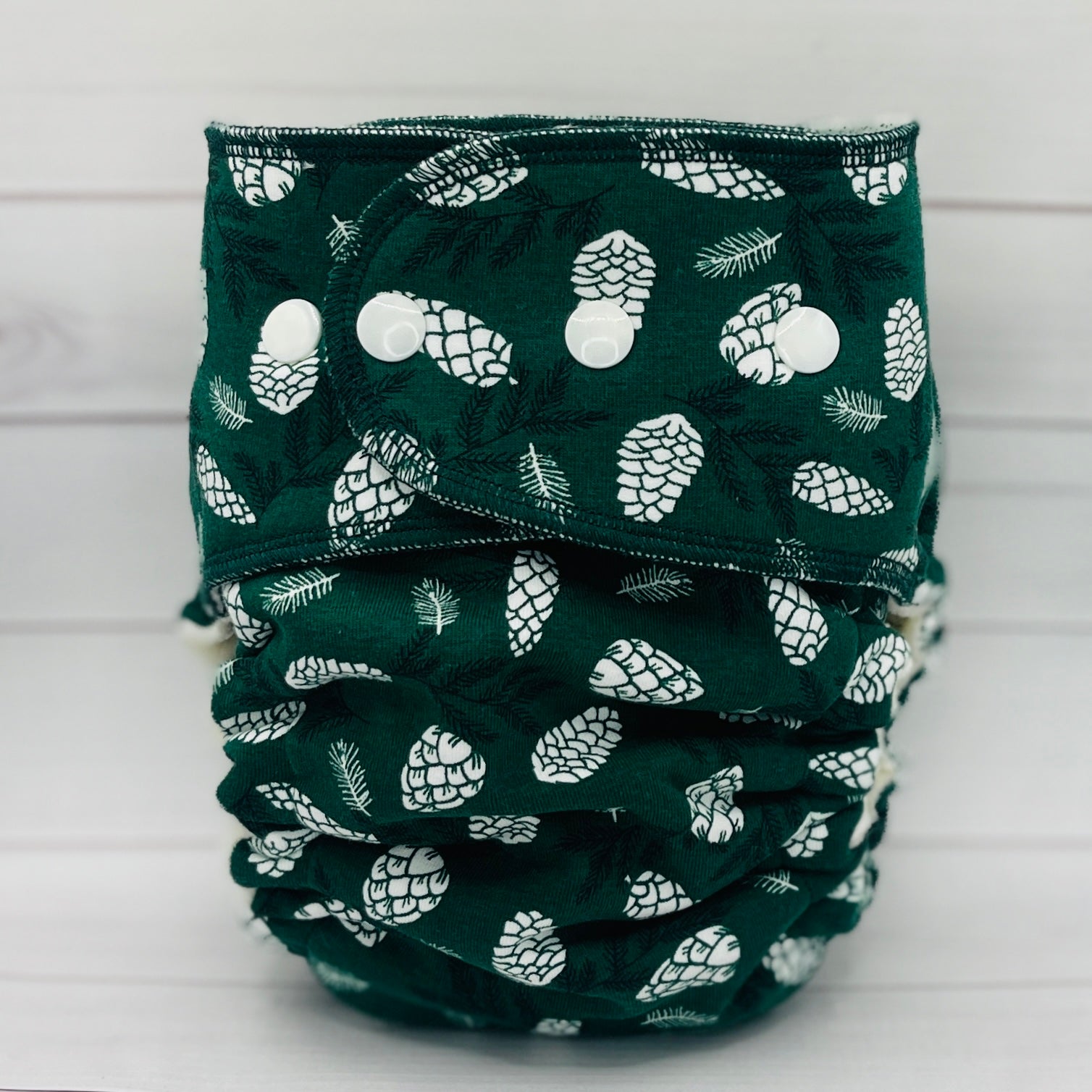 toddler fitted diaper with dark green print and white pinecones