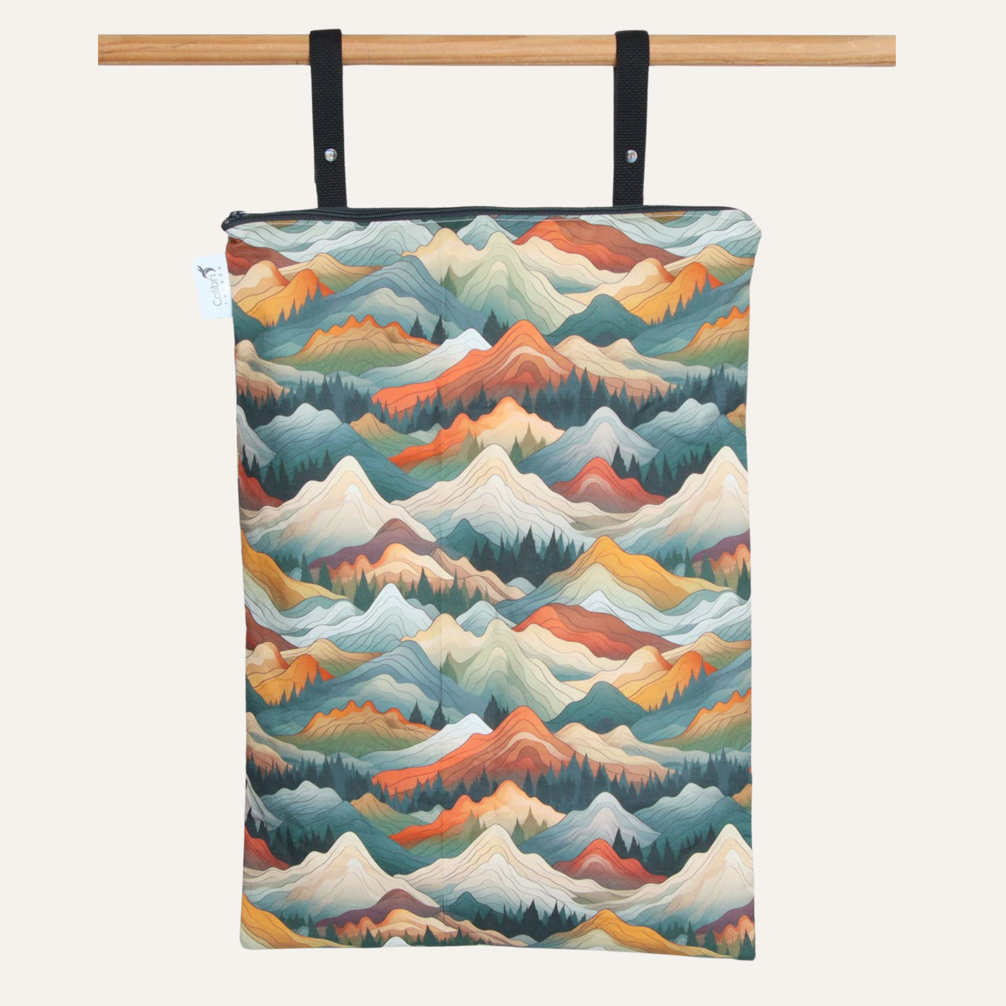 Towel with mountain pattern hanging on a wooden rod against a white background